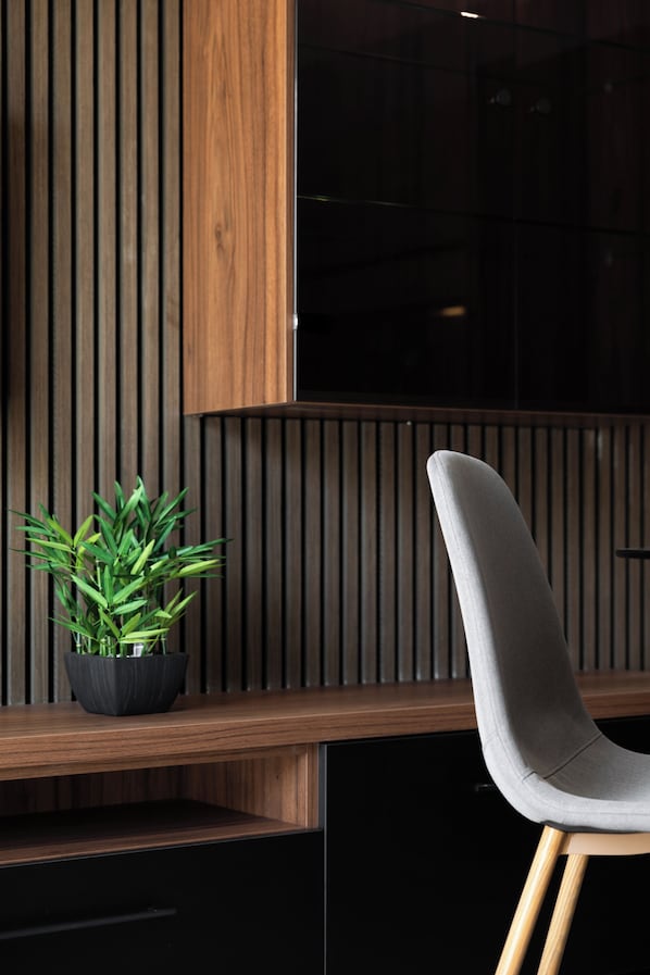 A modern interior with a wooden slat wall, a black cabinet, and a grey upholstered chair. - Modern 1BR APTS near Manoel & Tigne (Gżira)