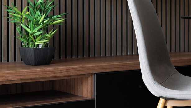 A modern interior with a wooden slat wall, a black cabinet, and a grey upholstered chair. - Modern 1BR APTS near Manoel & Tigne (Gżira)