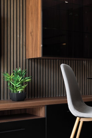A modern interior with a wooden slat wall, a black cabinet, and a grey upholstered chair. - Modern 1BR APTS near Manoel & Tigne (Gżira)