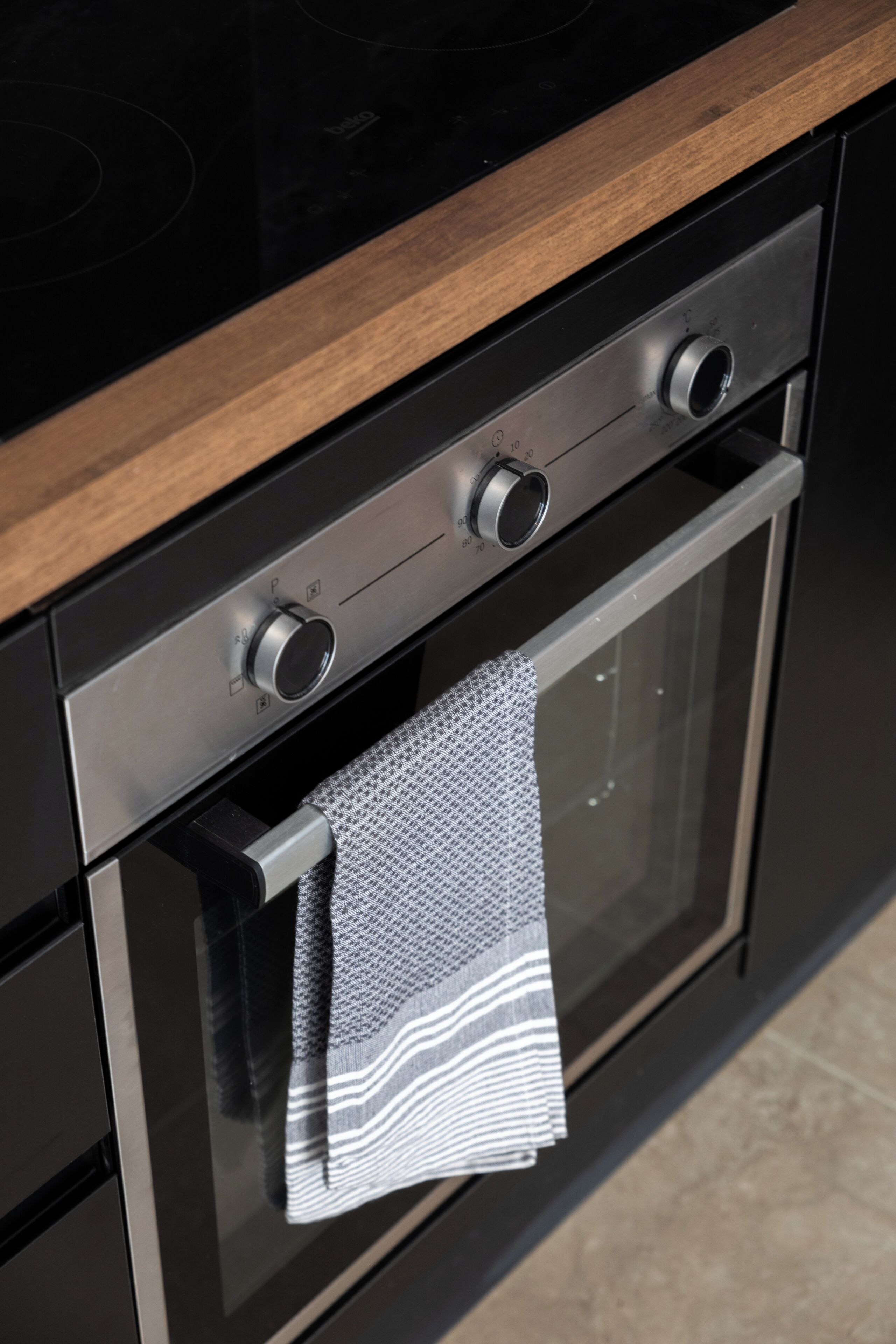 Une cuisine dotée d’un plan de travail en bois, d’appareils électroménagers en acier inoxydable et d’un torchon accroché à la porte du four.