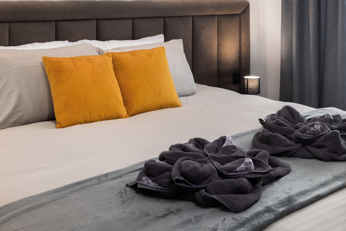 Une chambre d’hôtel avec un lit, un climatiseur fixé au mur, une lampe de chevet et une fenêtre avec des rideaux.