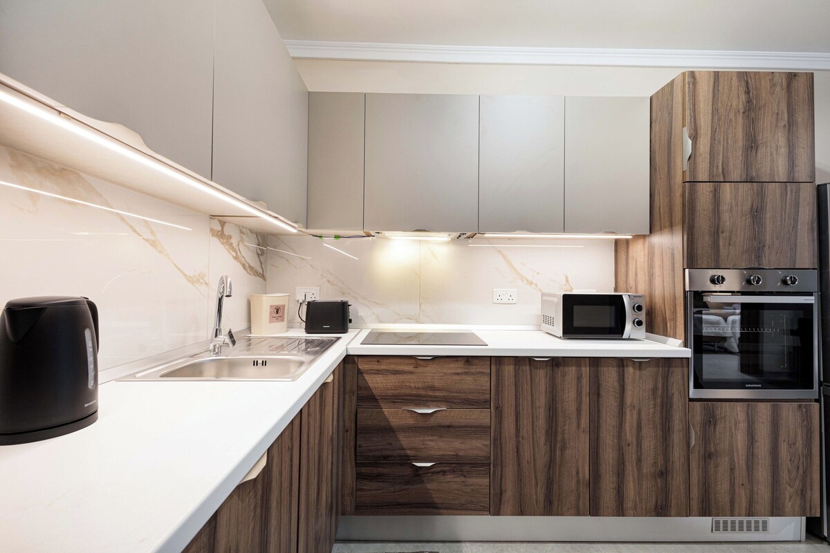 A modern kitchen with a marble backsplash, wooden cabinets, a built-in oven, and a microwave.