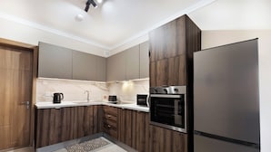 A modern kitchen with wooden cabinets, a stainless steel refrigerator, a built-in oven, and a microwave. - Luxury 1BR Stay at The Podium - Marina (Msida)