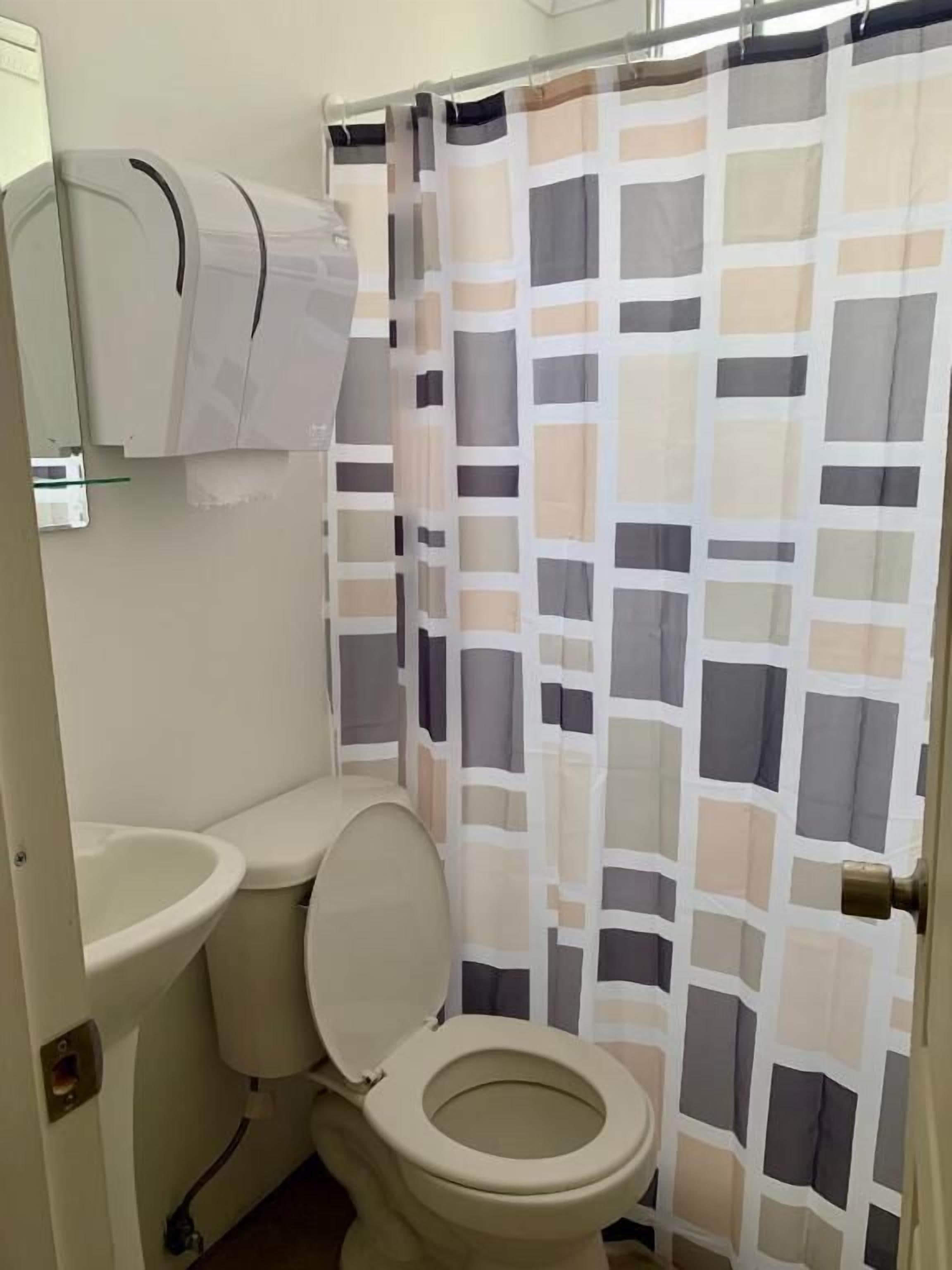 Un baño con inodoro, lavamanos y cortina de ducha.