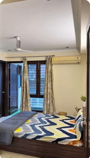 Ein Schlafzimmer mit einem Bett, Vorhängen, einem Deckenventilator und einem Fenster mit Jalousien.