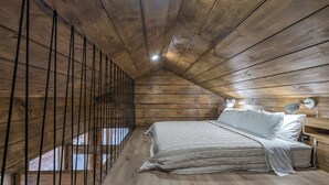 Un dormitorio de cabaña de madera con una cama, lámparas de noche y una ventana.