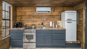 Cocina compacta con paredes de madera, horno empotrado, refrigerador y ventana con vistas.
