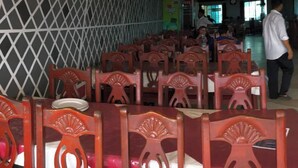 A dining area with rows of wooden chairs and tables, a decorative lattice wall, and a view of the dining area in the background. - Honeymoon Resorts Cox's Bazar (Cox's Bazar)