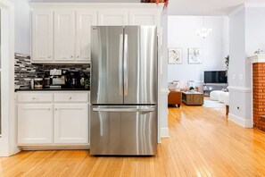 Eine moderne Küche mit einem Edelstahl-Kühlschrank mit zwei Türen, weißen Schränken und Holzboden.