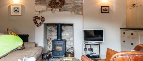 A cozy living room with a stone fireplace, a television, and leather furniture.