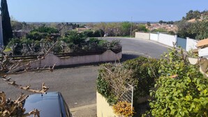 A residential area with a curved road, a parked car, and a view of the sea. - Bright studio apartment near the beaches – Portiragnes Village (Portiragnes)