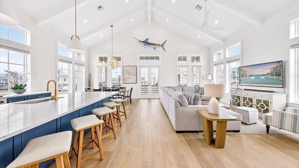 A spacious kitchen with a large island, bar stools, and a dining area with a sofa and table. - Spirit of the Ocean 404 RET (Port Aransas)