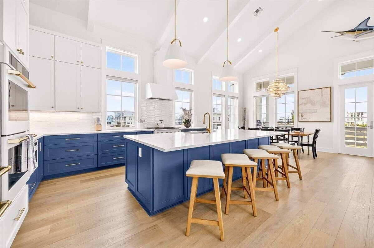Una cocina amplia con una isla grande, armarios blancos y detalles azules.