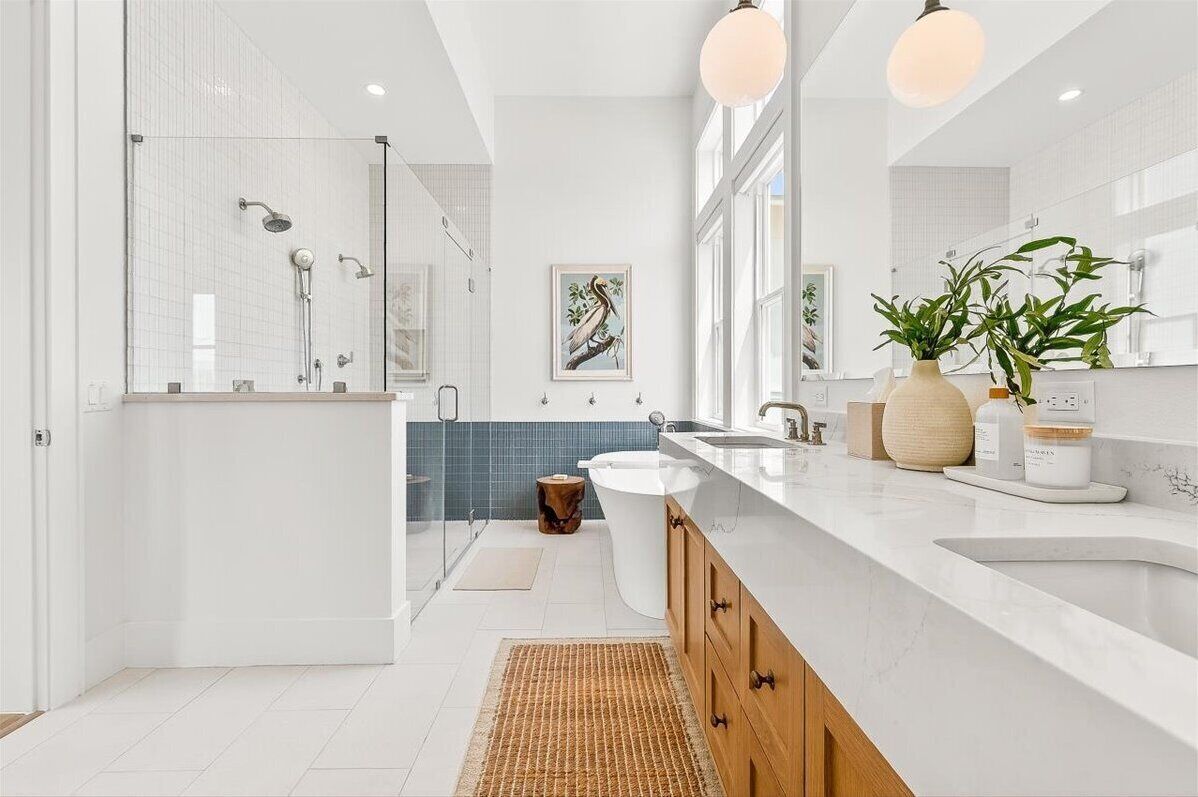 A modern bathroom with a glass shower enclosure, a white sink, and a large mirror.