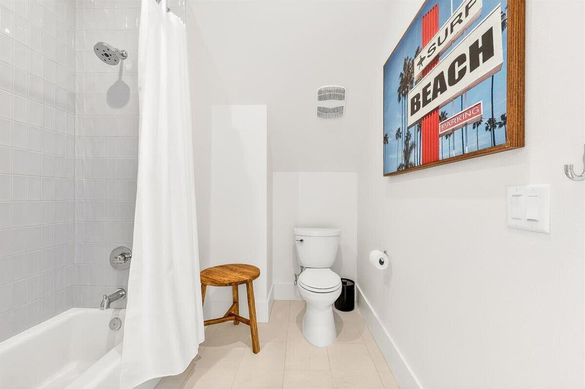 A bathroom with a bathtub, toilet, and a wooden stool.