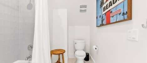 Un baño con bañera, inodoro y un taburete de madera.