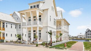 A multi-story white building with balconies, a covered porch, and a waterfront view. - Always Summer 157 DEW (Port Aransas)
