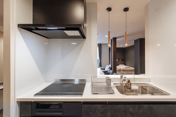 A modern kitchen with a built-in oven, a sink with a faucet, and a dish rack.