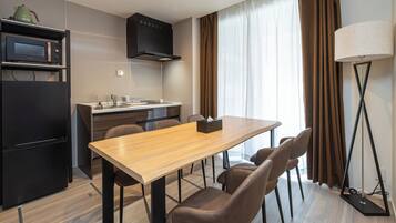 A modern kitchen with a microwave, stove, and sink, a dining table with chairs, and a floor lamp.