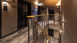 Interior moderno de hotel con escalera, ascensor y un cartel que indica el cuarto piso.