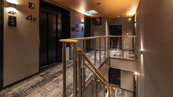 Interior moderno de hotel con escalera, ascensor y un cartel que indica el cuarto piso.