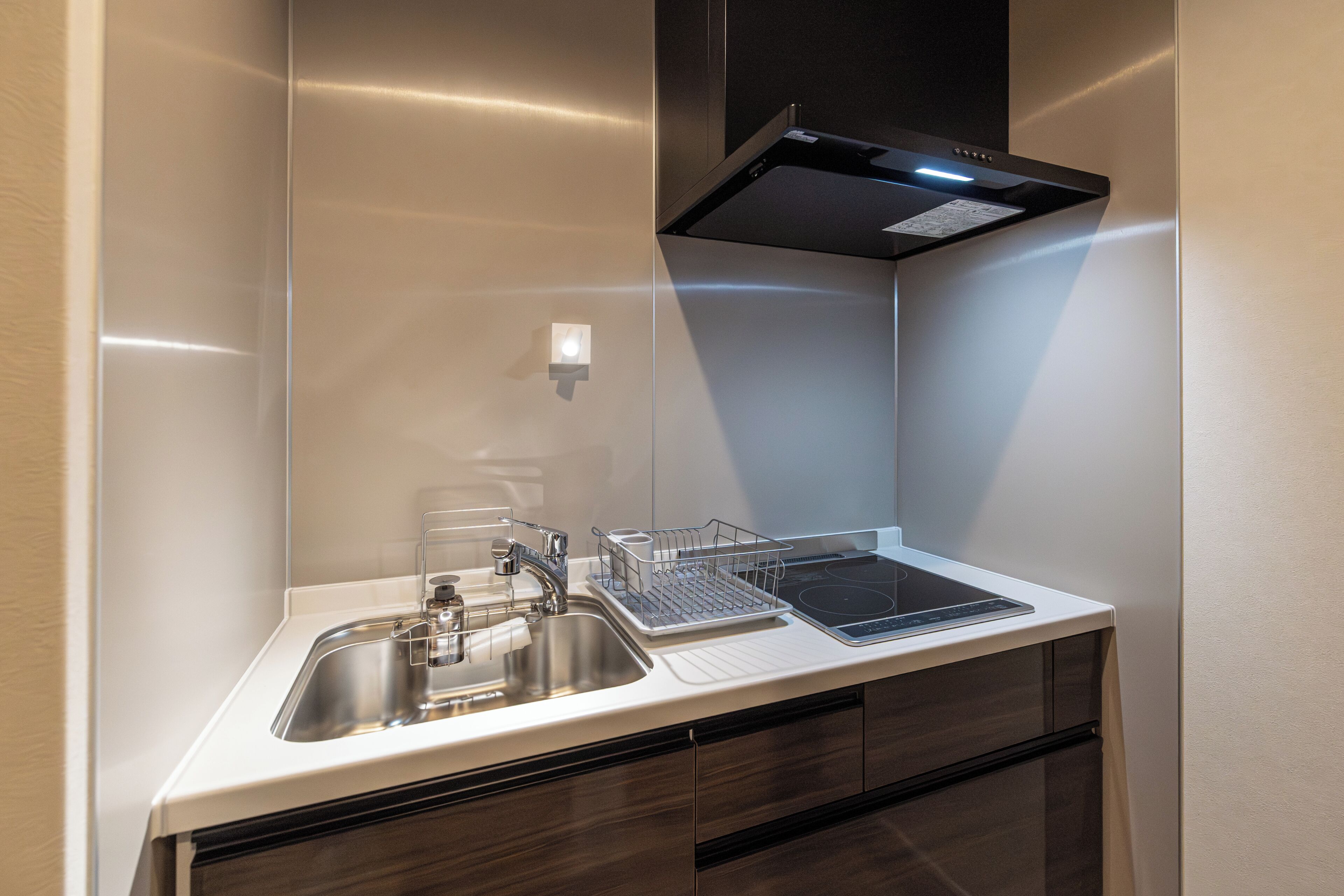 A modern kitchen with a stainless steel sink, a built-in oven, and a black range hood.