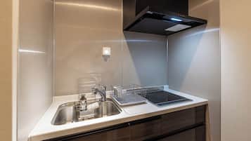 A modern kitchen with a stainless steel sink, a built-in oven, and a black range hood.