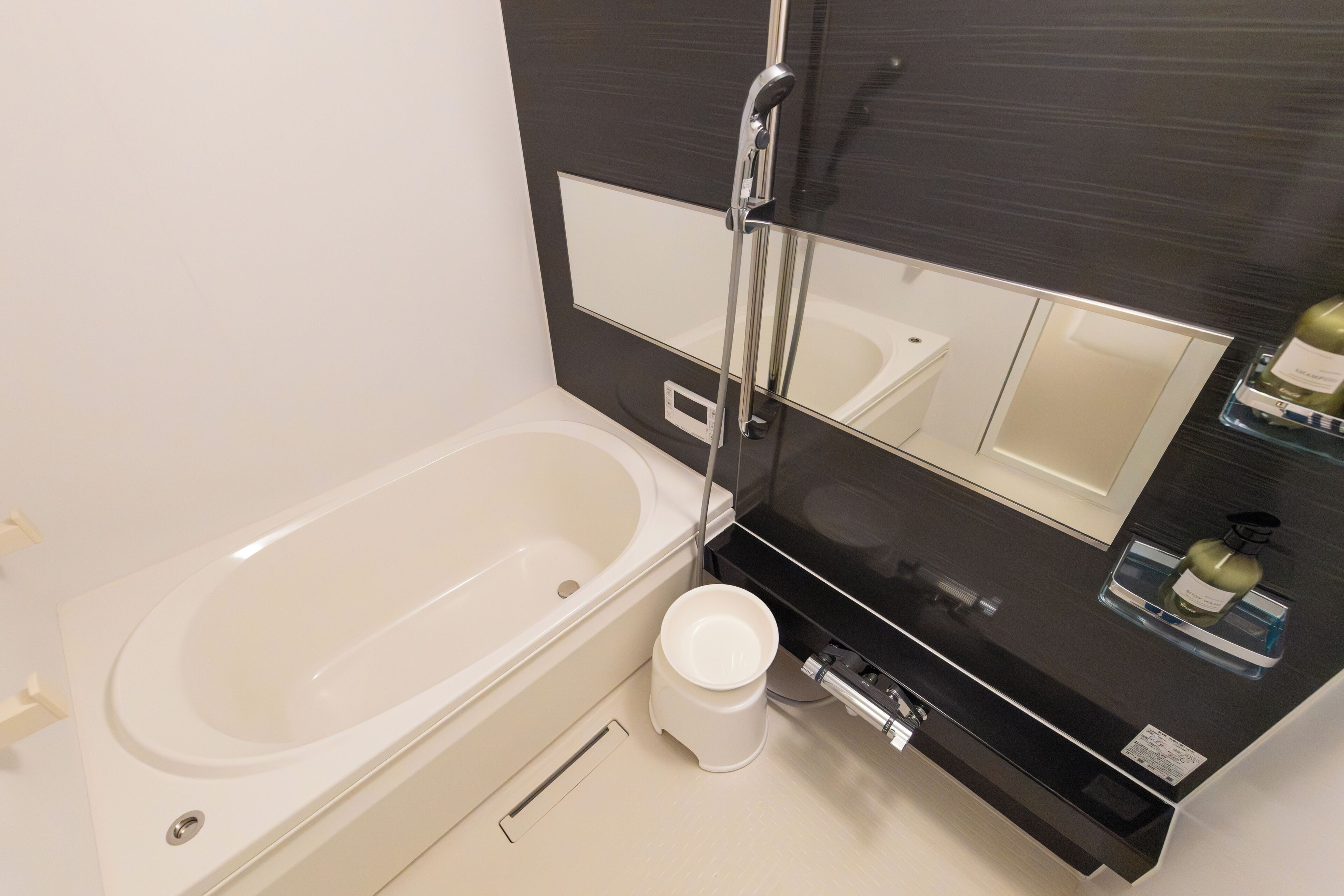 A modern bathroom with a bathtub, a toilet, a bidet, and a large mirror.