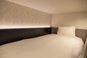 Una cama bien hecha con cabecera, un muro con estampado y una pared lisa.