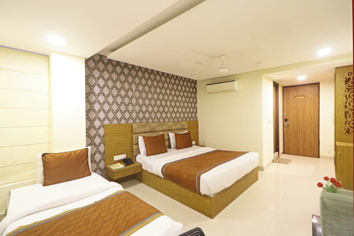 A hotel room with two beds, a wooden headboard, a nightstand, and a wall-mounted air conditioner.