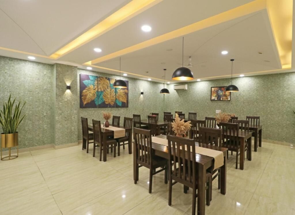 Un espace repas avec plusieurs tables et chaises, un grand tableau au mur et des luminaires au plafond.