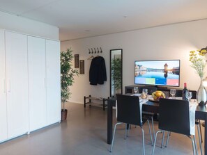 A modern dining area with a television, chairs, a table, and a potted plant. - Apartment  by Interhome (Lucerne)