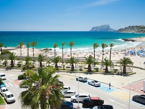 Blick auf einen Strand mit Parkplatz, Palmen und freier Meerblick.