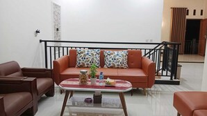A living room with a sofa, two armchairs, a coffee table, and a staircase. - Borobudur Daleme Make Homestay (Borobudur)