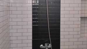A shower enclosure with a black door, white tiled walls, and a window above. - Borobudur Daleme Make Homestay (Borobudur)