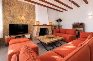 Ein Wohnzimmer mit Steinwand, Kamin, Flachbildfernseher und orangefarbener Möbel.