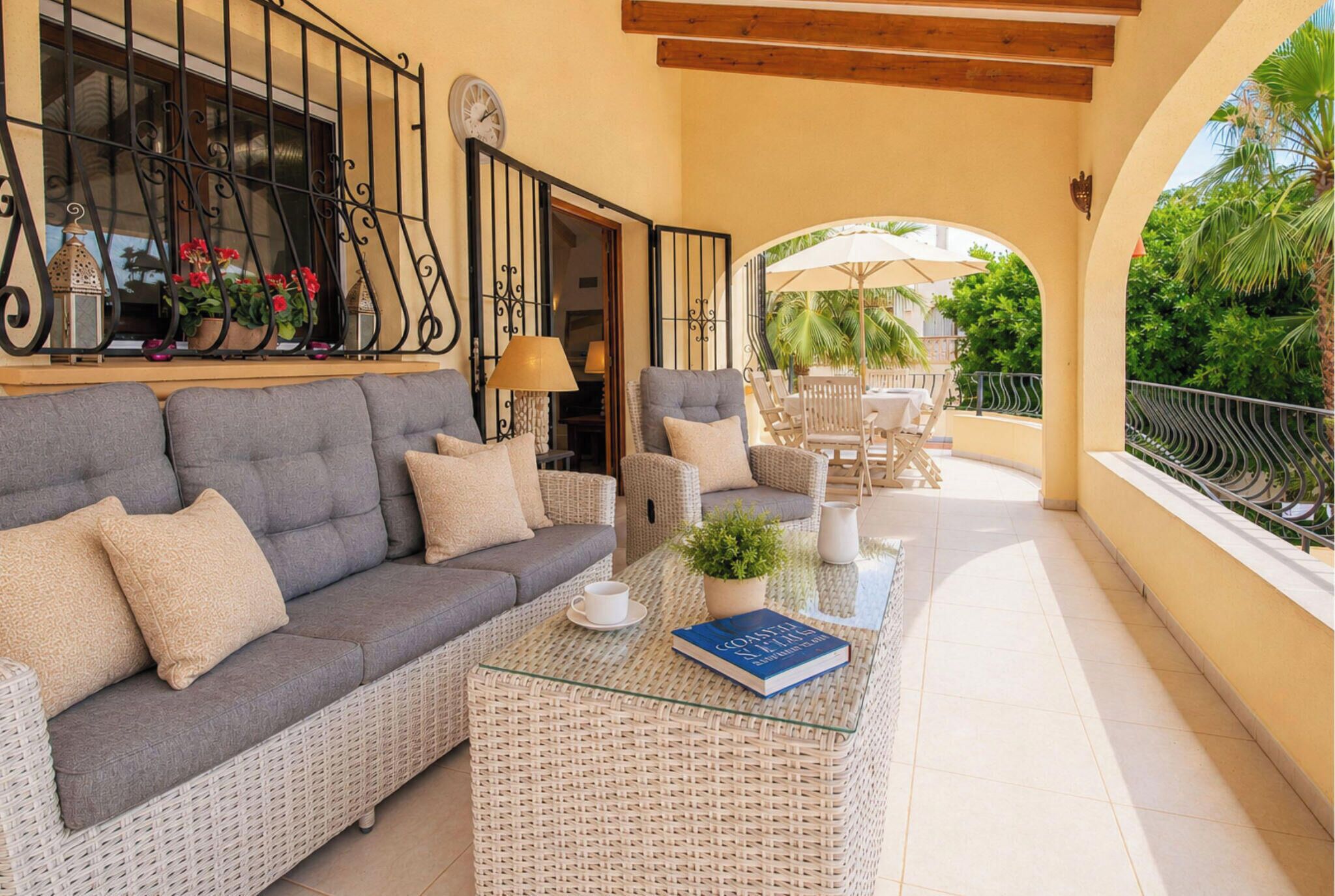 A covered outdoor seating area with a sofa, chairs, and a coffee table.
