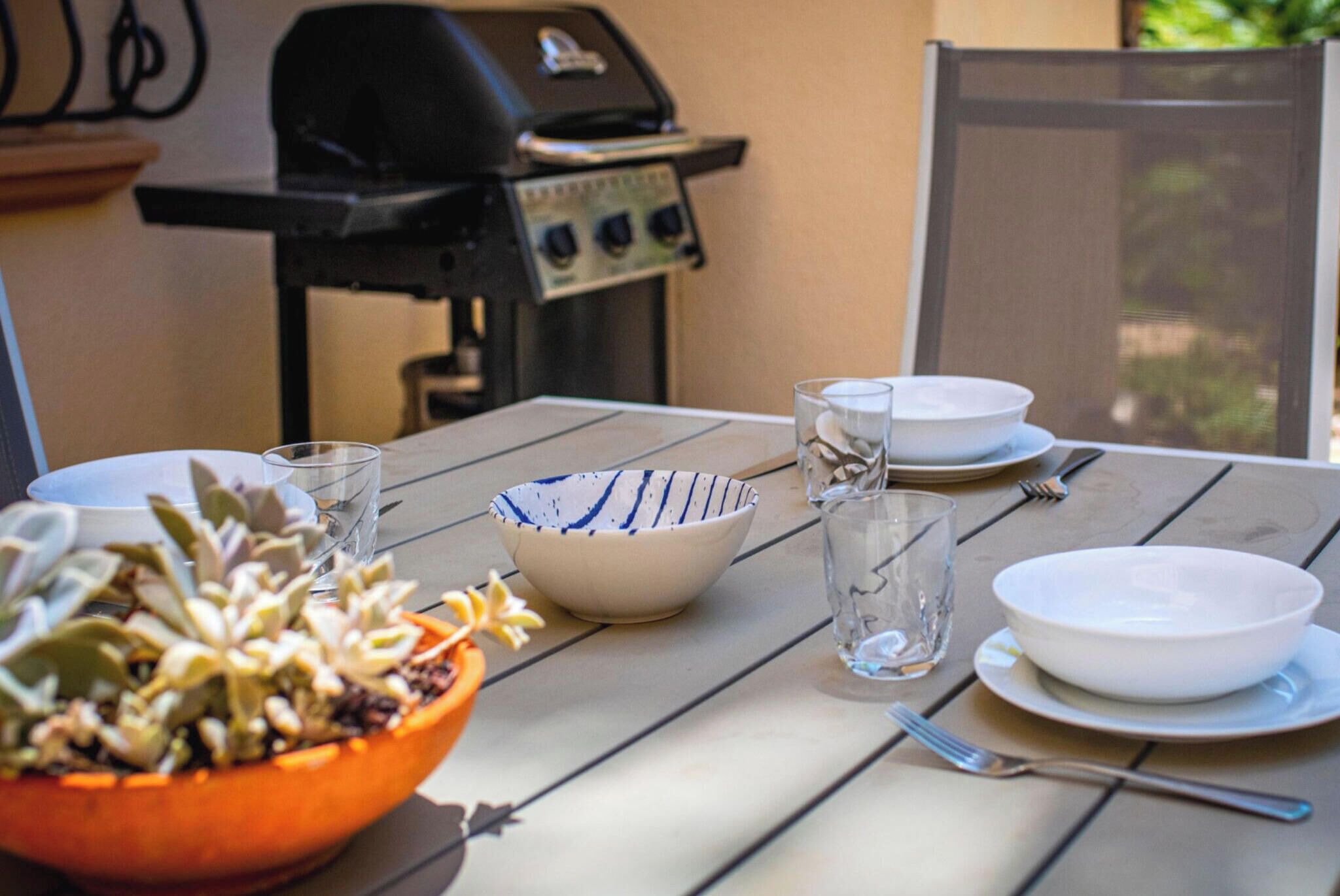 Een gedekte tafel met een saladeschaal, borden, glazen en bestek.