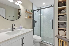 A modern bathroom with a glass shower enclosure, a white sink, and a toilet. - The Perfect CDA Escape - Beach, Trails & Downtown All Within Walking Distance (Coeur d'Alene)