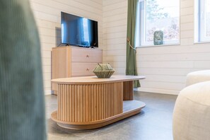 A modern room with a wooden console table, a flat-screen TV, and a window with a view. - Gite - 3 bedrooms - sleeps 6 (ROBELMONT)