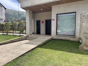 Une entrée d’immeuble avec une façade en béton, une grande fenêtre et une porte portant l’inscription « VT ».