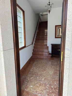 Un escalier avec une rampe, un lustre et une porte dotée d’une poignée en laiton.