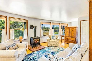 A spacious room with a fireplace, large windows, a sofa, and a wooden cabinet.