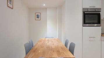 A modern kitchen with a built-in oven and a dining area with a wooden table and chairs.