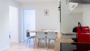 Uma cozinha moderna com um fogão vermelho, uma mesa de jantar de madeira com quatro cadeiras e uma pequena moldura na parede.