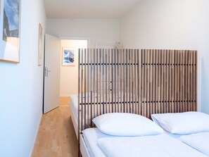 A hotel room with a bed, a wooden headboard, a door, and a framed picture on the wall. - Apartment  by Interhome (Lucerne)