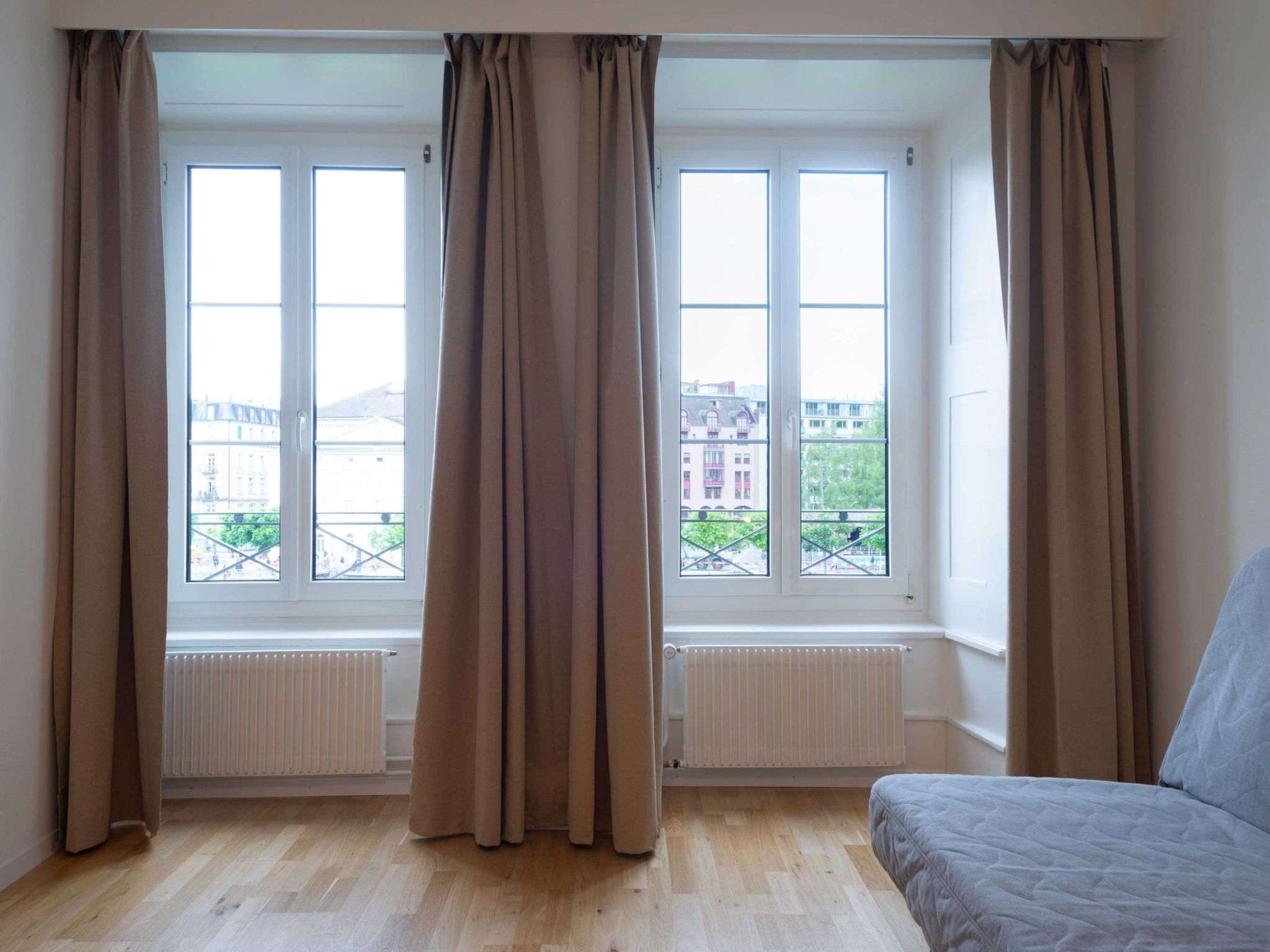 Una habitación con dos ventanas, un radiador y una cama.