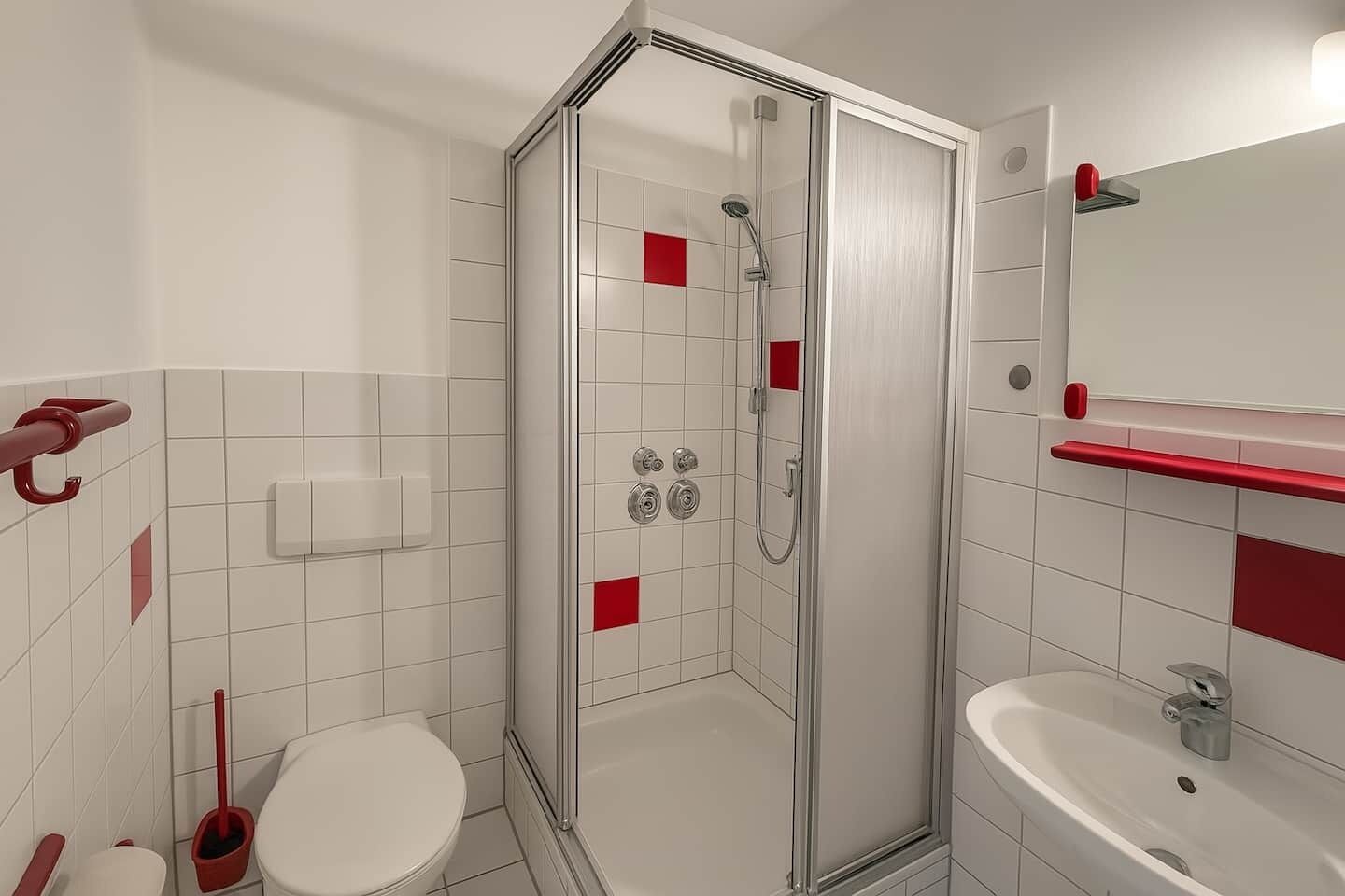 Une salle de bain moderne avec une douche à parois de verre, des toilettes blanches et un lavabo avec un miroir au-dessus.