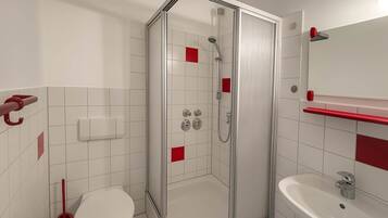 Une salle de bain moderne avec une douche à parois de verre, des toilettes blanches et un lavabo avec un miroir au-dessus.