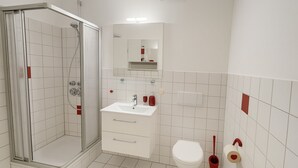 A bathroom with a shower, sink, toilet, and a mirror above the sink. - BoardingHouse - Studios & Apartments (Kassel)